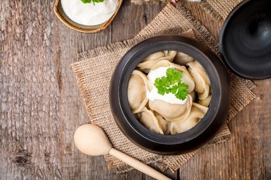 meat dumplings - russian pelmeni with sour cream on rustic background, top view