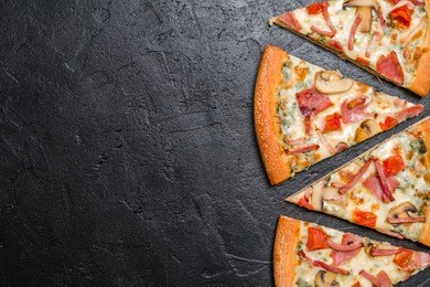 cut into slices delicious fresh pizza with mushrooms and ham on a dark background. top view . pizza on the black table.