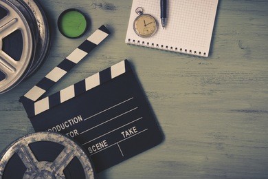 clapperboard and a film reel, a stop watch, a notebook and a lens on the table