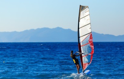 recreational water sports. windsurfing. windsurfer surfing the wind on waves in ocean, sea. extreme sport action. recreational sporting activity. healthy active lifestyle. summer fun adventure. hobby