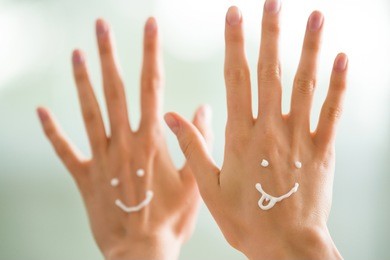 closeup woman beautiful hands with long fingers applying moisturising and soothing cream on skin. funny smiling faces, emoji.