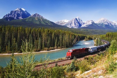 train passing through bow valley under the surveillance of mighty rocky mountains.