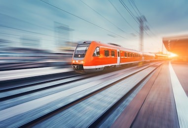 modern high speed red passenger commuter train in motion at the railway platform at sunset. railway station. railroad with motion blur effect. industrial landscape with train. vintage toning