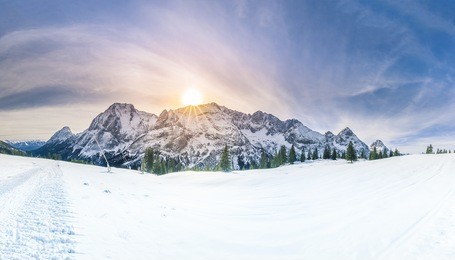 winter sunshine over snowy mountains - snowy panorama with the austrian alps, the green coniferous forests and a valley covered by white snow.