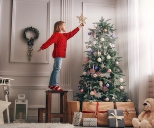 merry christmas and happy holidays!  cute little child girl is decorating the christmas tree indoors.