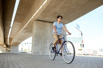 people, style, leisure and lifestyle - young hipster man riding fixed gear bike on city street