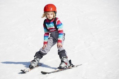happy child girl enjoying vacation in winter resort. little girl skiing in mountains. active sportive toddler wearing helmet learning to ski. winter sport for family. skier racing in snow.