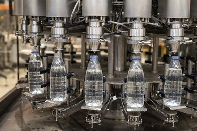 plastic liter bottles on the assembly line packaging machine pouring. packing shrink food equipment