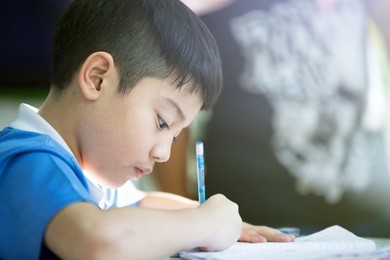 young asian boy doing his homework , with sun light .