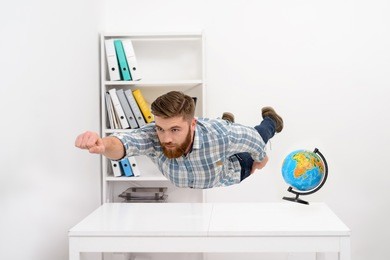 concentrated bearded man in plaid shirt flying above office desk 