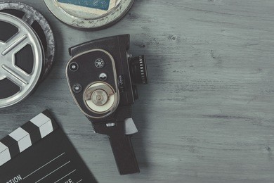 old movie camera with film reels and a clapper board lying on the painted table