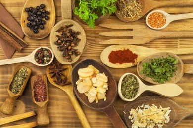 various kinds of spices on the kitchen table. seasoning food. sales of exotic spices. advertising on spices. powder spices on spoons in wooden table background.