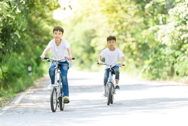 young thai boy ride bicycle on the road in the park.