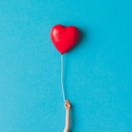 doll hand with heart shaped baloon. minimal concept. flat lay.