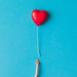 doll hand with heart shaped baloon. minimal concept. flat lay.