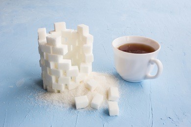 sugar castle built out of sugar cubes, sugar tower, sugar walls, blue background, ruins, broken, cup