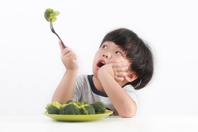 little asian boy refuse to eat healthy vegetables.