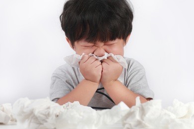 sick little asian boy wiping or cleaning nose with tissue isolated white background
