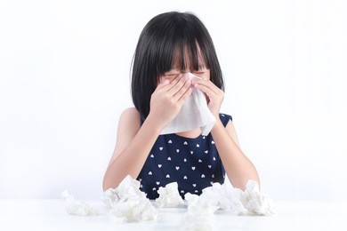 sick little asian girl wiping or cleaning nose with tissue isolated white background
