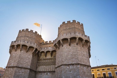 exterior  facade of serranos gate or serranos towers, part of the ancient city wall of valencia, spain. valencia flag flying from the top of the building.