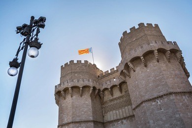 exterior  facade of serranos gate or serranos towers, part of the ancient city wall of valencia, spain. valencia flag flying from the top of the building.