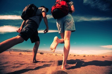 two hikers walking forward in the sandy desert of the death valley national park, usa
