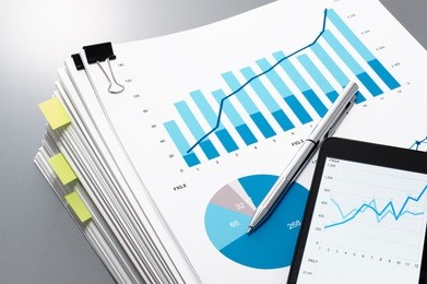 pile of documents, smart phone and pen on gray reflection background. many graphs and charts. concept image of data gathering.
