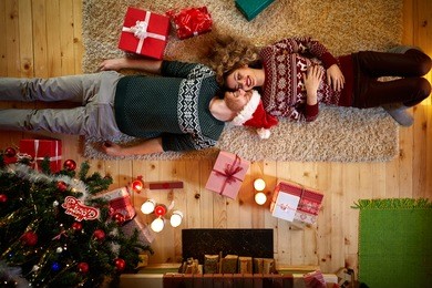  man and woman lying on the floor in christmas decorated home 