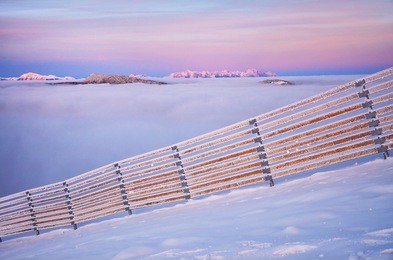 winter landscape shortly before sunset. view on valley full of clouds an colored mountains in background