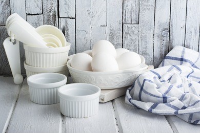 ceramic white form for baking and village eggs on the kitchen simple white wooden background with blue dining cotton towel. horizontal. selective focus