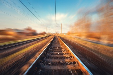 railroad in motion at sunset. railway station with motion blur effect against beautiful blue sky, industrial concept background. railroad travel, railway tourism. blurred railway. transportation