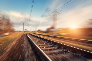 railroad in motion at sunset. railway station with motion blur effect against beautiful blue sky, industrial concept background. railroad travel, railway tourism. blurred railway. transportation