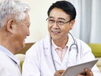 asian doctor talking to a senior patient, happy and smiling