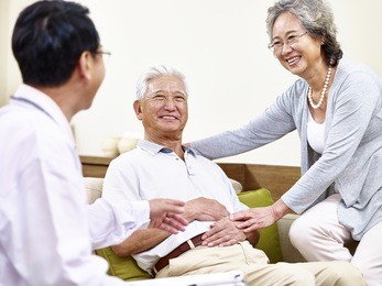 senior asian patient being taken care of by his wife and a family doctor