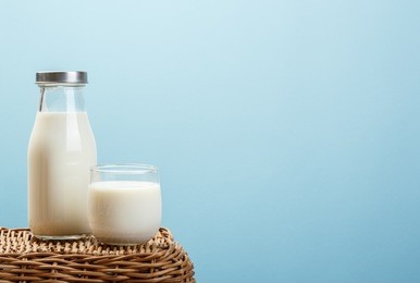 a bottle of rustic milk and glass of milk on wicker on a blue background, nutritious and healthy dairy products concept
