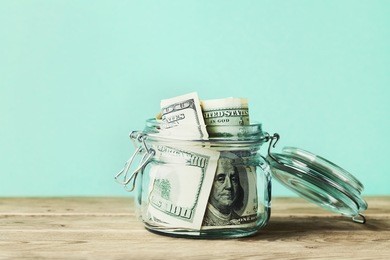 dollar bills in glass jar on wooden table. saving money concept.
