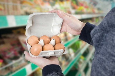 man holding egg box in supermarket. egg box buy carton man hold checking consumer concept
