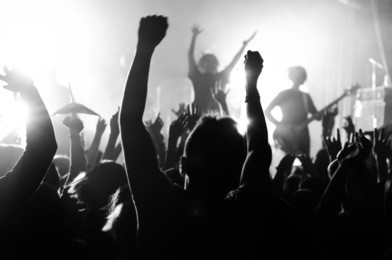 silhouettes of people at a concert in front of the scene in bright light. black and white