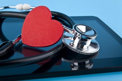 stethoscope, heart and tablet on blue background closeup