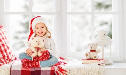 happy child girl sitting in the winter window christmas