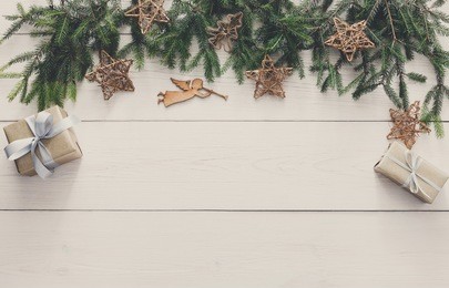 christmas decoration, gift boxes and garland frame concept background, top view with copy space on white wood table surface. christmas ornaments and presents border