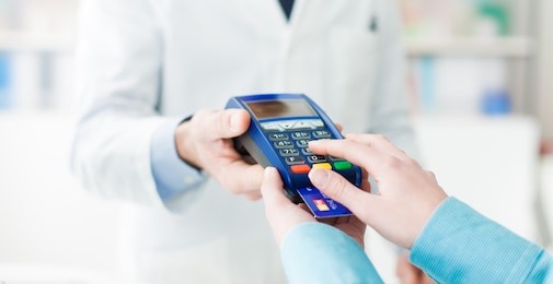 woman shopping at the pharmacy with a credit card and entering a security pin on the terminal, hands close up