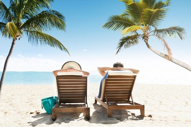rear view of couple relaxing on lounge enjoying vacation on beach