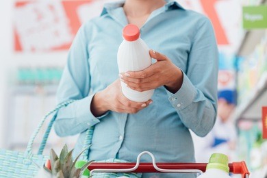 woman doing grocery shopping at the supermarket and reading food labels, nutrition and quality concept