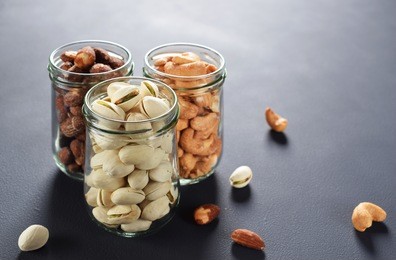 healthy roasted nuts (cashew nut, almond, and pistachio) in glass bottles on dark background