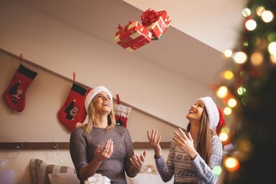 smiling girls throwing their christmas gifts in the air.