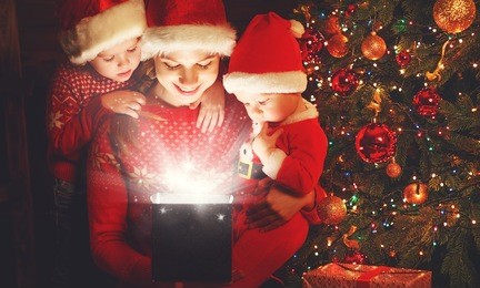 happy family on christmas eve. mother and children discover a magical gift at the tree