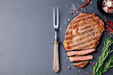 grilled sliced beef steak on slate stone table. top view. copy space