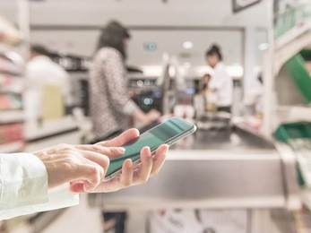 digital lifestyle business person or shopper using mobile smart phone for retail shopping in supermarket at cashier counter