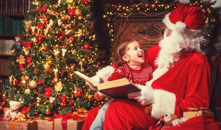 happy child girl hugging santa reading book and laughs